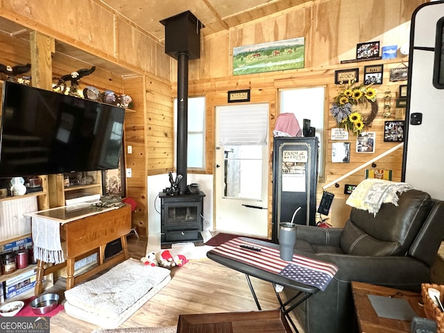 living room with wood-type flooring, a wood stove, and wooden walls