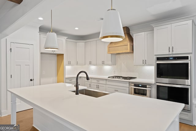 kitchen featuring premium range hood, sink, decorative light fixtures, and appliances with stainless steel finishes