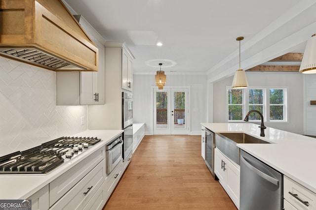 kitchen featuring appliances with stainless steel finishes, decorative light fixtures, white cabinetry, and custom range hood