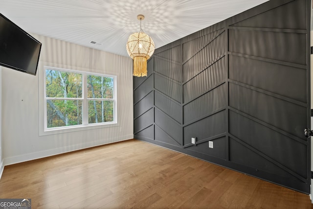 empty room featuring hardwood / wood-style floors and an inviting chandelier