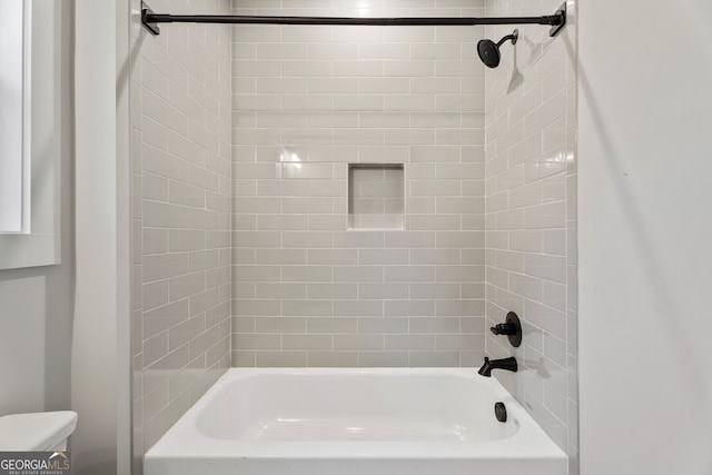 bathroom with tiled shower / bath combo and toilet