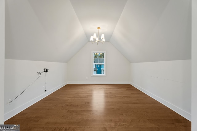 additional living space with a chandelier, dark hardwood / wood-style flooring, and vaulted ceiling