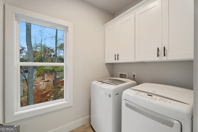 laundry area with washer and clothes dryer, cabinets, and light hardwood / wood-style flooring