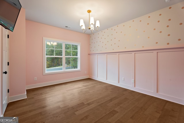 unfurnished room featuring wood-type flooring and an inviting chandelier