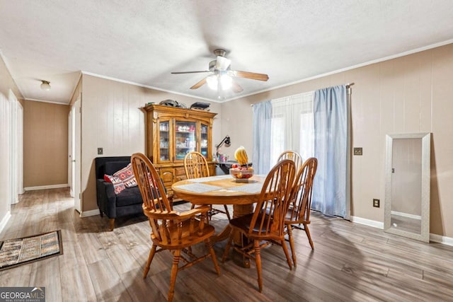 dining area featuring ceiling fan, light hardwood / wood-style floors, a textured ceiling, and ornamental molding