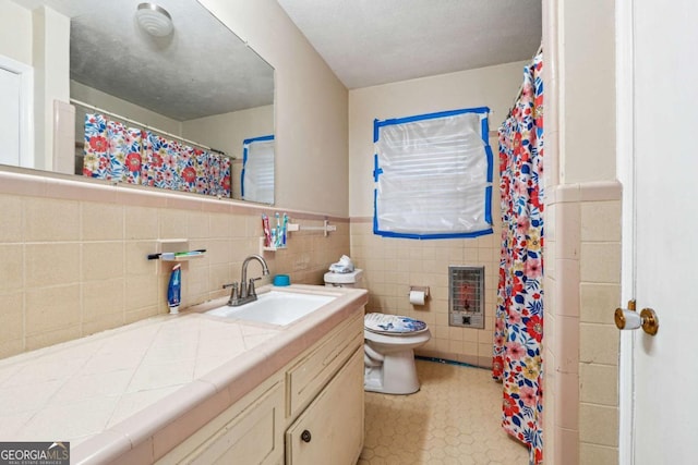 bathroom featuring vanity, heating unit, toilet, and tile walls