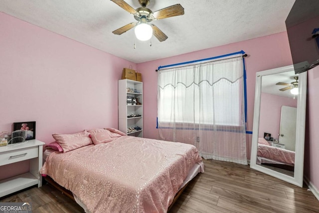 bedroom featuring ceiling fan, wood-type flooring, and a textured ceiling