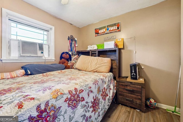 bedroom with hardwood / wood-style flooring, ceiling fan, and cooling unit