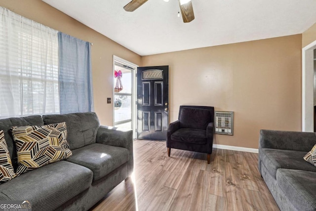 living room featuring heating unit, ceiling fan, and light hardwood / wood-style flooring