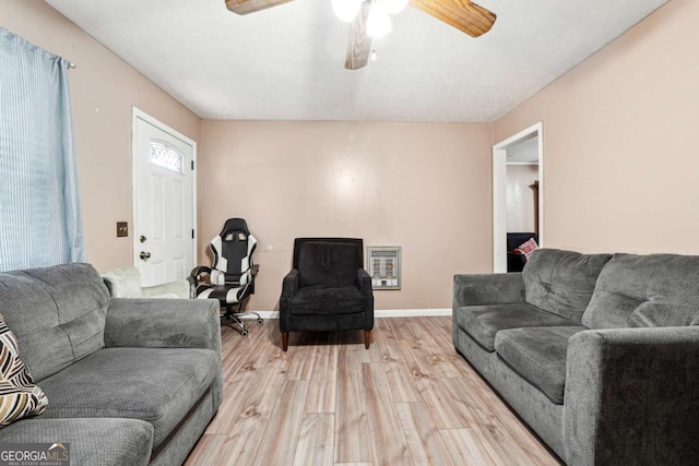 living room with heating unit, light hardwood / wood-style flooring, and ceiling fan