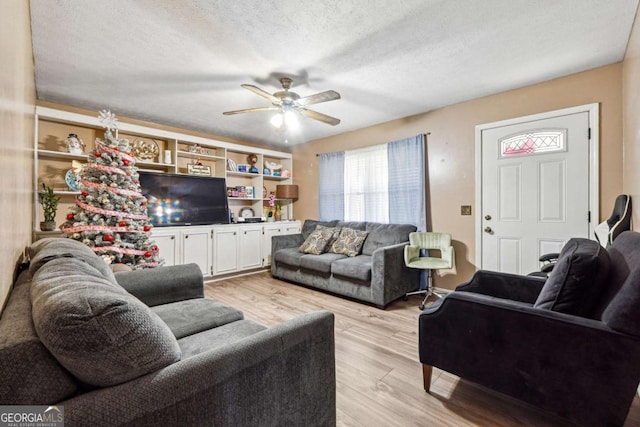 living room with light wood-type flooring, a textured ceiling, and ceiling fan