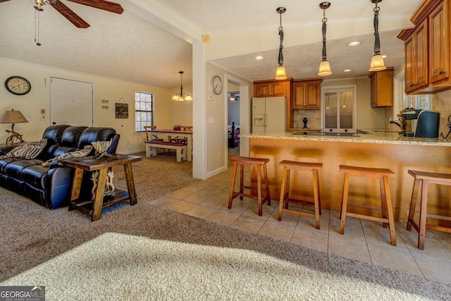 kitchen featuring a kitchen breakfast bar, ceiling fan with notable chandelier, light colored carpet, decorative light fixtures, and white fridge with ice dispenser