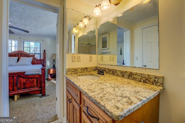 bathroom featuring ceiling fan, vanity, a textured ceiling, and ornamental molding