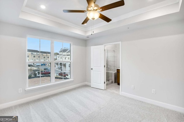 unfurnished bedroom featuring ceiling fan, light colored carpet, connected bathroom, and a tray ceiling