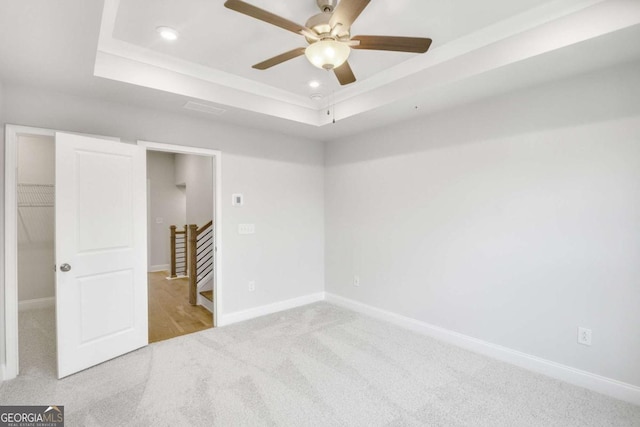 spare room with a tray ceiling, ceiling fan, and light colored carpet