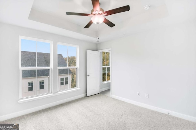 carpeted empty room featuring ceiling fan and a tray ceiling