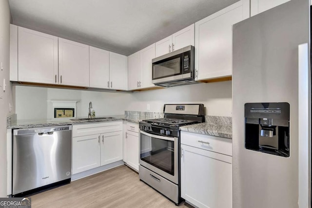 kitchen with white cabinetry, sink, stainless steel appliances, and light hardwood / wood-style floors