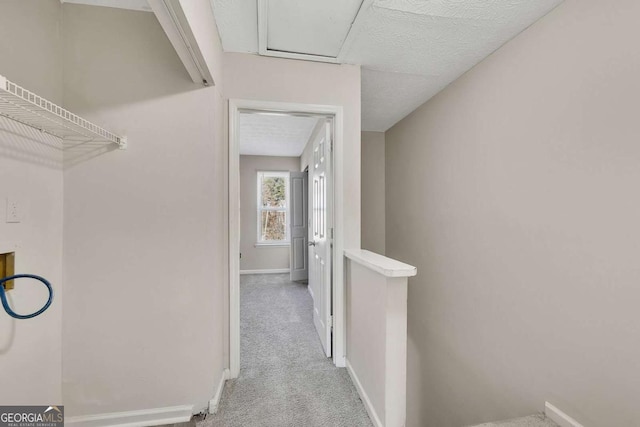 hallway featuring light carpet and a textured ceiling