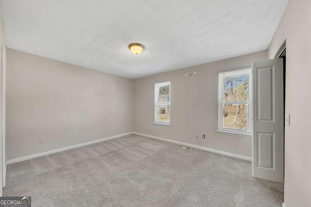 carpeted empty room featuring a textured ceiling