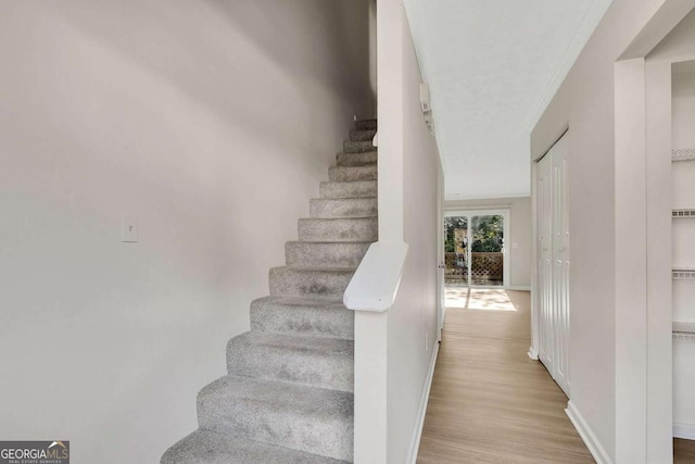 staircase featuring hardwood / wood-style flooring and crown molding