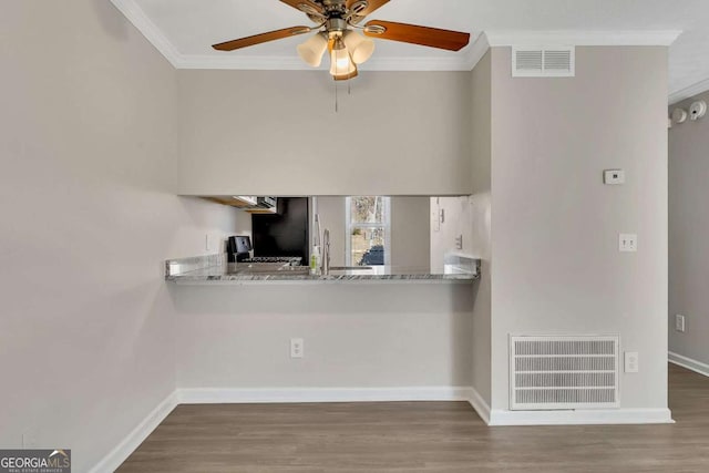 kitchen with stainless steel fridge, crown molding, and light stone countertops