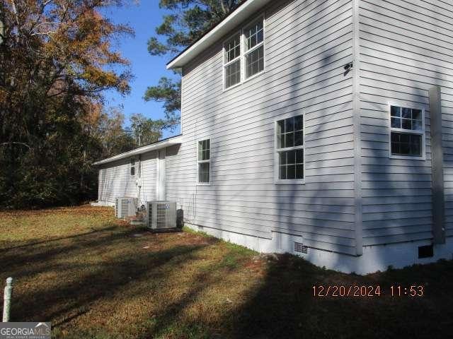 view of side of property with central AC and a yard