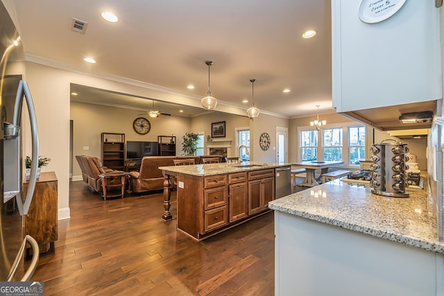 kitchen featuring light stone countertops, a large island, hanging light fixtures, and ceiling fan with notable chandelier