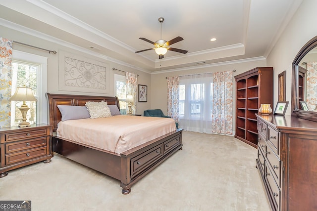 bedroom with ceiling fan, crown molding, light carpet, and a tray ceiling