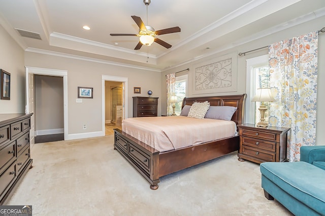 bedroom with ceiling fan, a raised ceiling, multiple windows, and ensuite bath