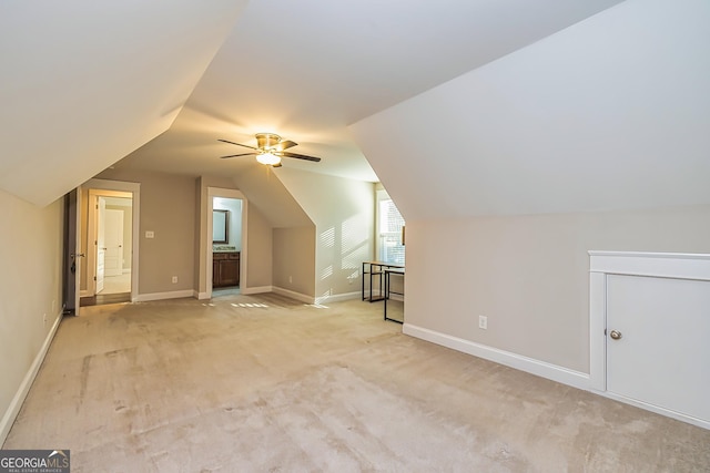 additional living space with ceiling fan, light colored carpet, and vaulted ceiling