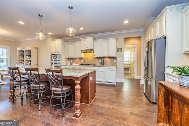 kitchen featuring light stone countertops, stainless steel appliances, an island with sink, pendant lighting, and a breakfast bar area