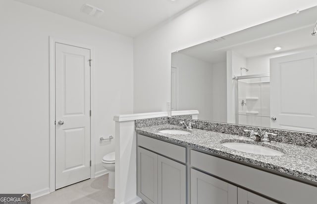 full bathroom featuring toilet, double vanity, a sink, and a shower with shower door