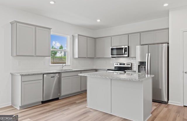 kitchen featuring stainless steel appliances, light wood-style floors, a sink, and gray cabinetry