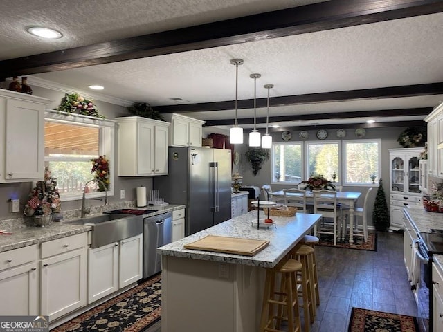 kitchen with stainless steel appliances, sink, pendant lighting, a center island, and white cabinetry