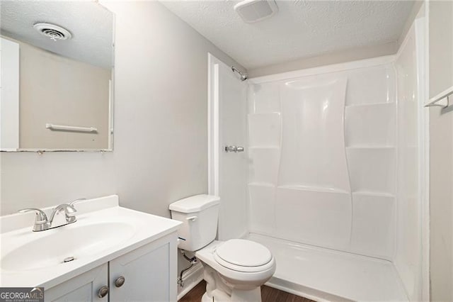 bathroom featuring a shower, vanity, a textured ceiling, and toilet