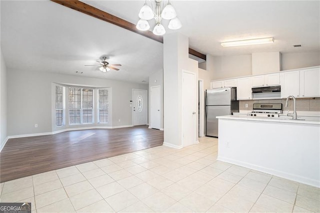 kitchen featuring ceiling fan with notable chandelier, stainless steel appliances, sink, vaulted ceiling with beams, and white cabinetry