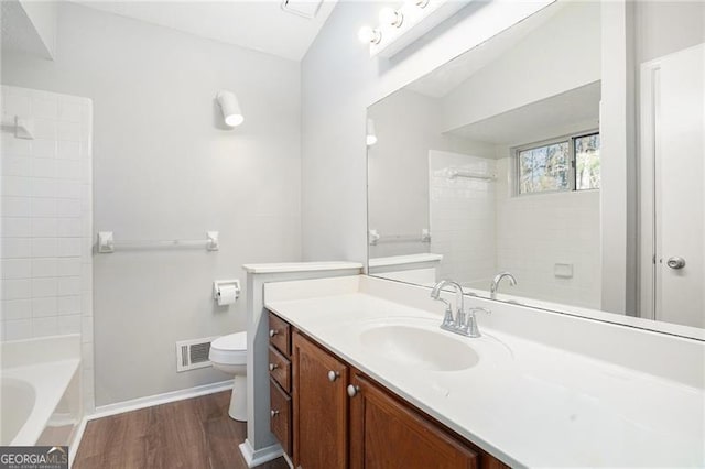 full bathroom with tiled shower / bath combo, vanity, hardwood / wood-style flooring, toilet, and lofted ceiling