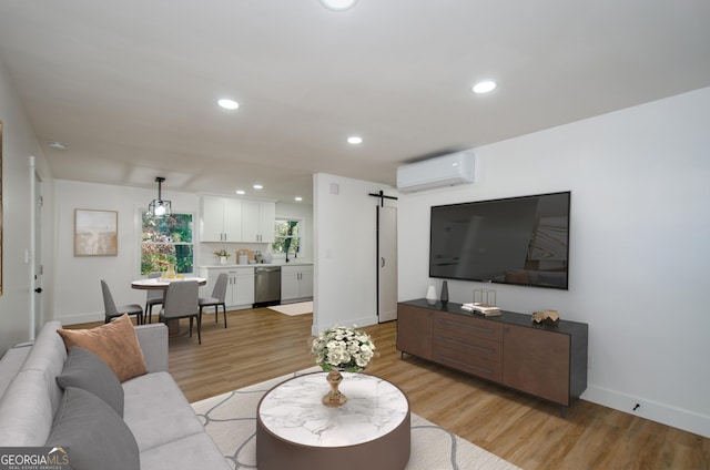 living room with a barn door, sink, a wall mounted air conditioner, and light hardwood / wood-style floors