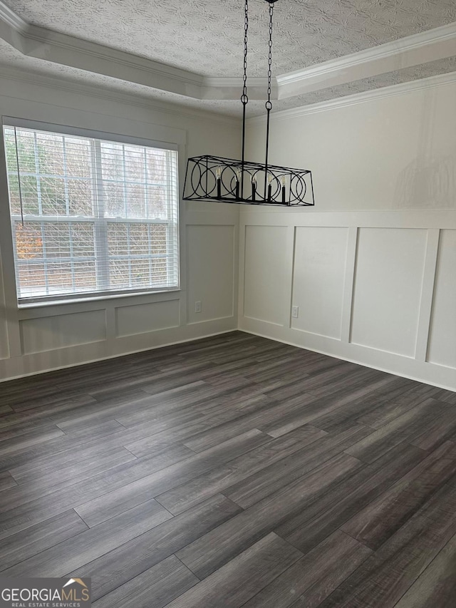 unfurnished dining area featuring ornamental molding, a textured ceiling, a raised ceiling, and dark wood-type flooring