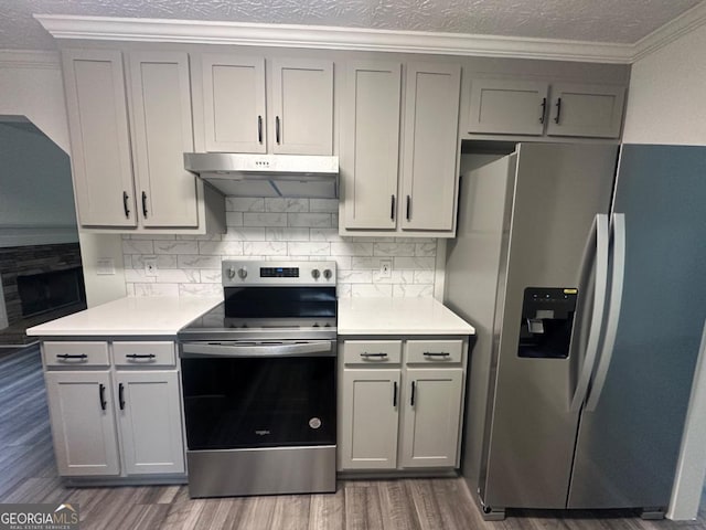 kitchen featuring tasteful backsplash, dark hardwood / wood-style flooring, stainless steel appliances, and ornamental molding