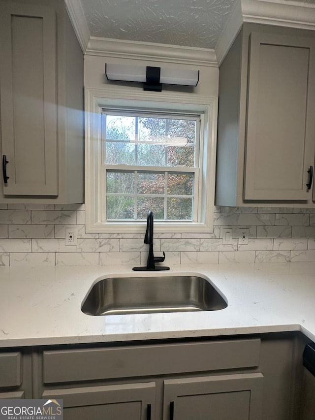 kitchen with gray cabinetry, crown molding, sink, and tasteful backsplash