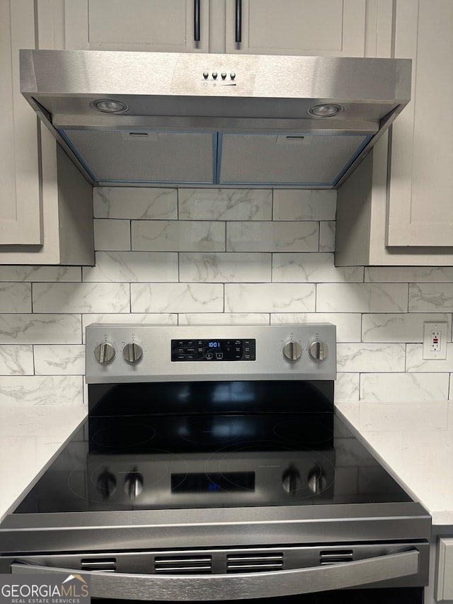 kitchen with stainless steel electric range, decorative backsplash, and exhaust hood