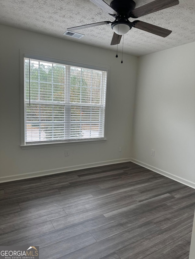 spare room with a textured ceiling, dark hardwood / wood-style flooring, and plenty of natural light