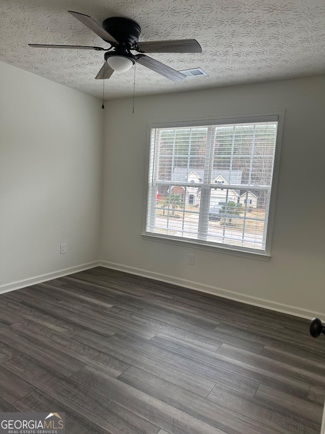 unfurnished room featuring dark hardwood / wood-style flooring, a textured ceiling, ceiling fan, and a healthy amount of sunlight