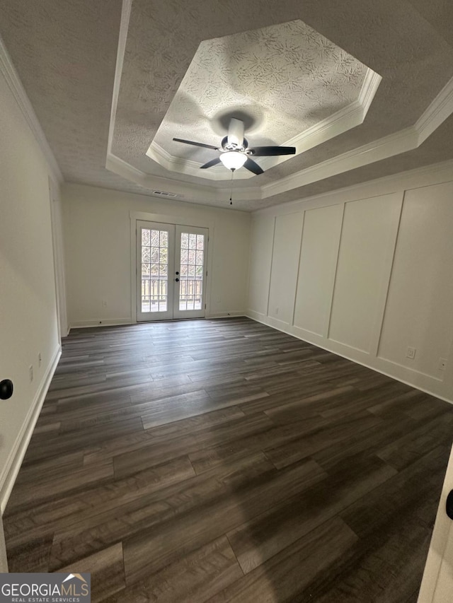 empty room featuring ceiling fan, french doors, ornamental molding, and a tray ceiling