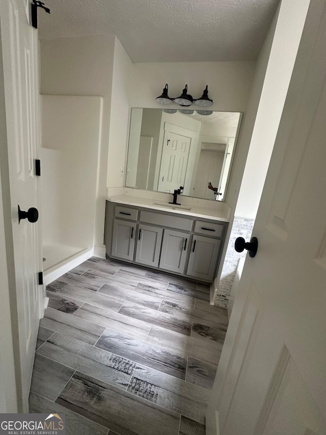 bathroom with a shower, a textured ceiling, and vanity