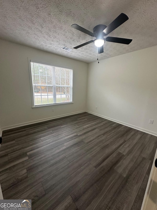 spare room with ceiling fan, dark wood-type flooring, and a textured ceiling