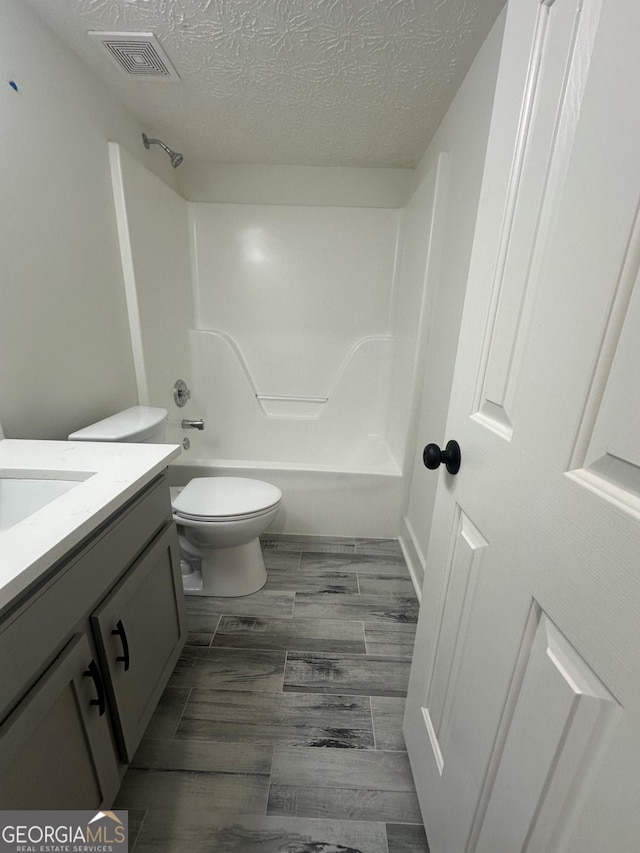 full bathroom with toilet, vanity, a textured ceiling, and bathing tub / shower combination