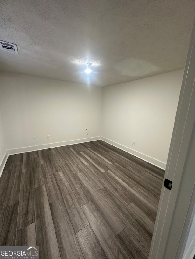 spare room with dark hardwood / wood-style flooring and a textured ceiling