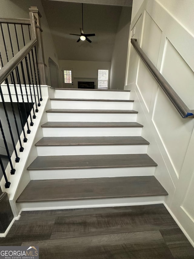 stairs featuring ceiling fan and hardwood / wood-style floors